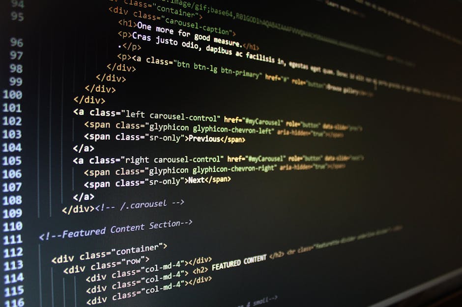 A close-up view of a computer screen displaying lines of HTML code in a dark environment, with syntax highlighting showing tags and text in various colors including green, yellow, and white. The code 